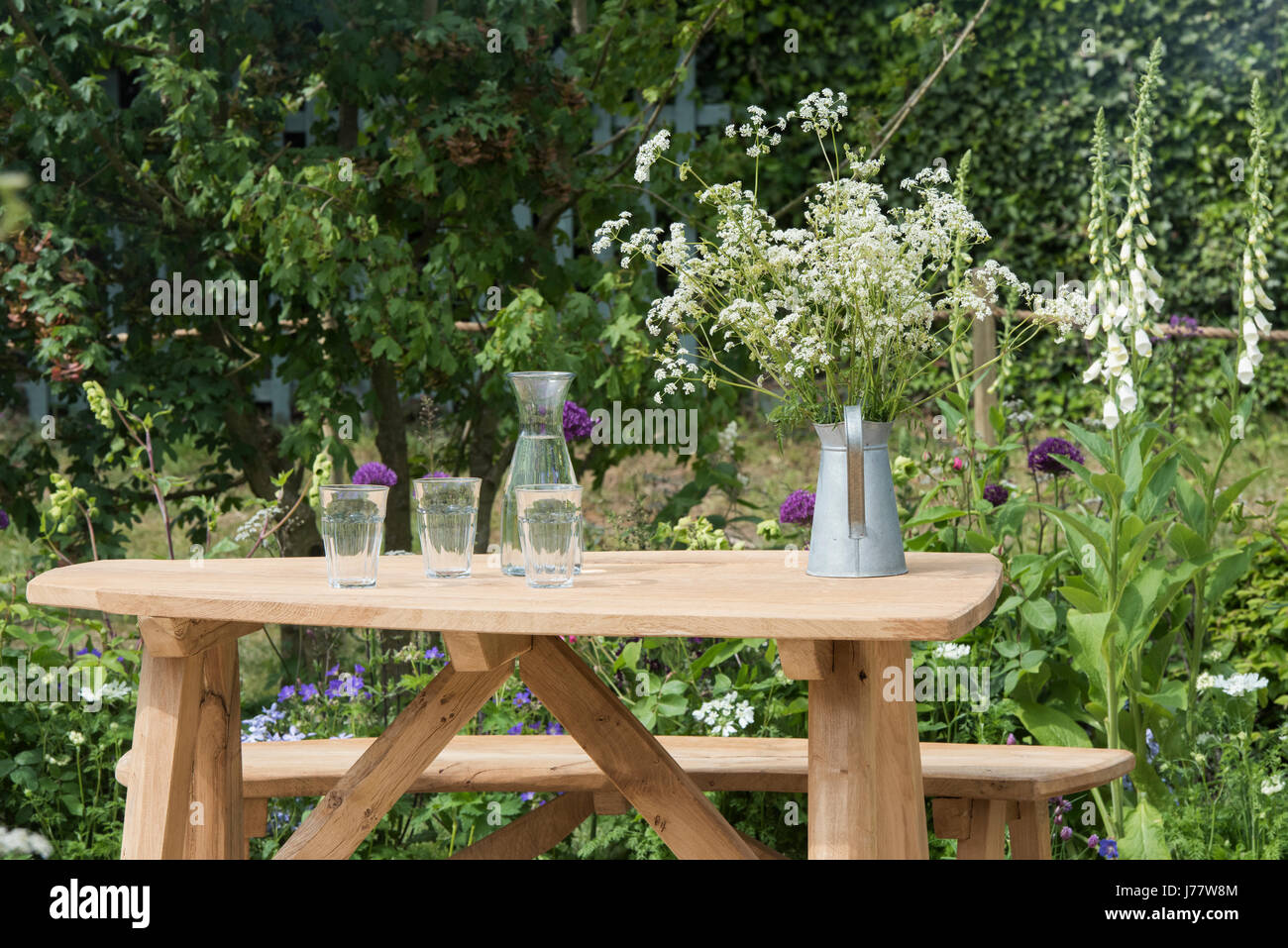 Glaskanne, Trinkgläser und ein Metall geschnittenen Kuh Petersilie auf einem Holztisch Garten voller Krug. UK Stockfoto