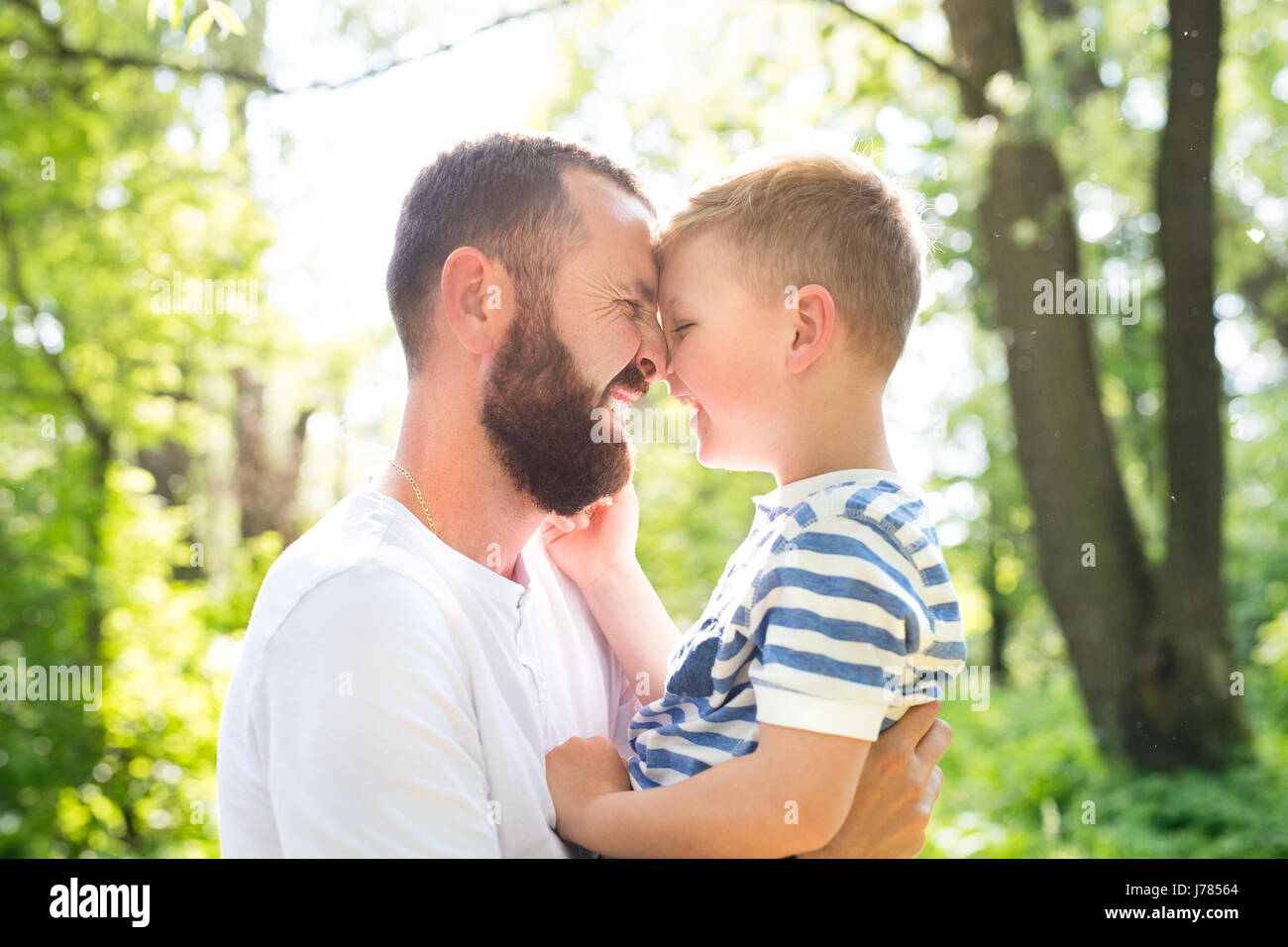 Junger Vater mit kleinen Sohn in grünen Wäldern, sonnigen Tag. Stockfoto