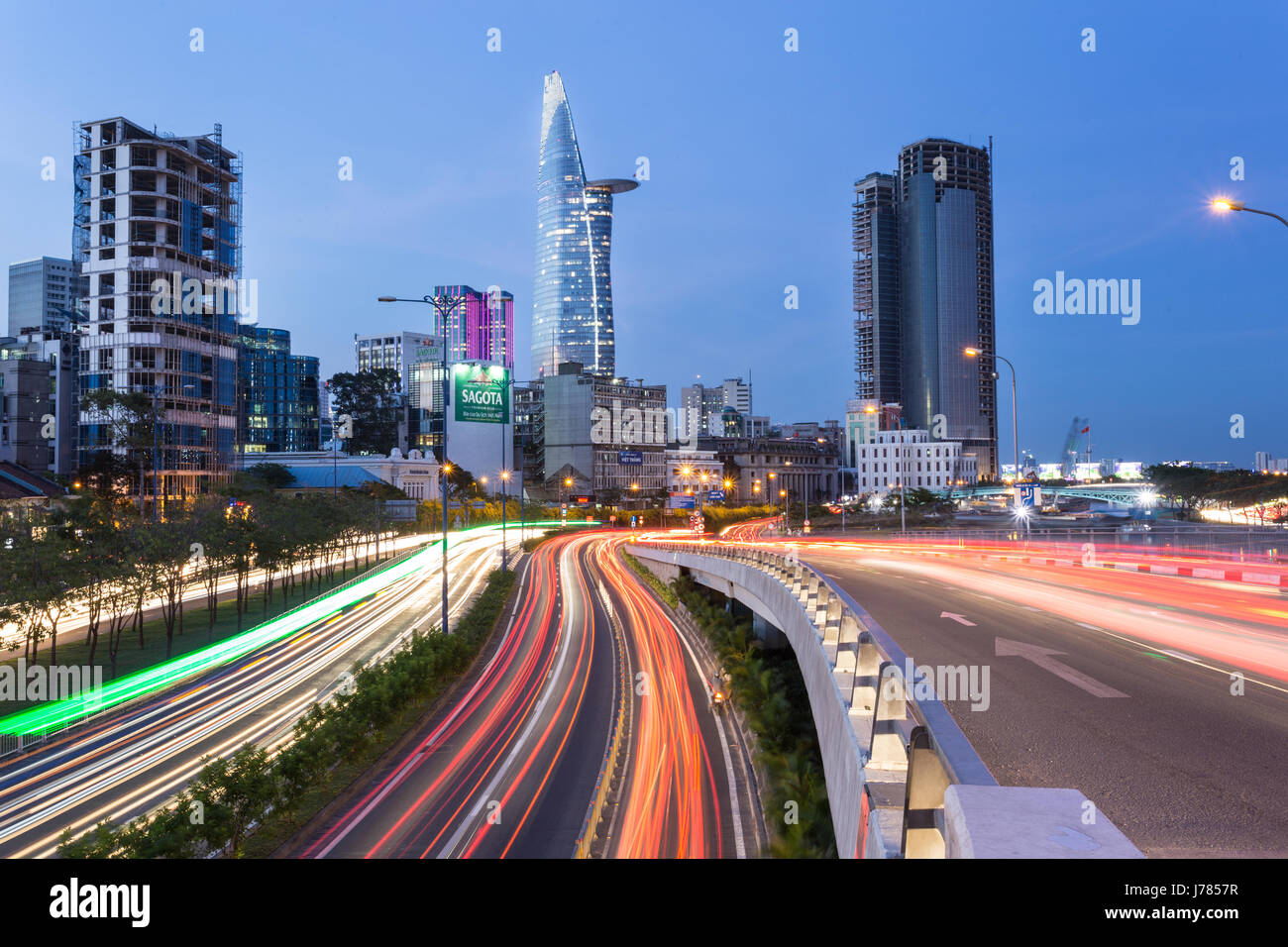 HO-CHI-Minh-Stadt, VIETNAM - 14. April 2017: Verkehr eilt entlang den Autobahnen in Ho-Chi-Minh-Stadt mit der Skyline des Geschäftsviertels in Vietnam Stockfoto