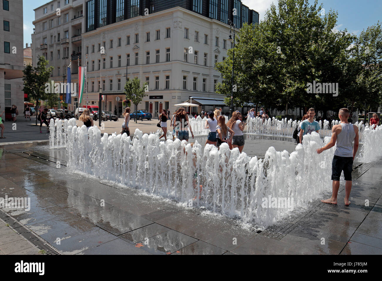 Menschen spielen mit dem interaktiven Brunnen (es reagiert auf Menschen, die durch ihn) am Platz der Freiheit, Budapest, Ungarn. Stockfoto