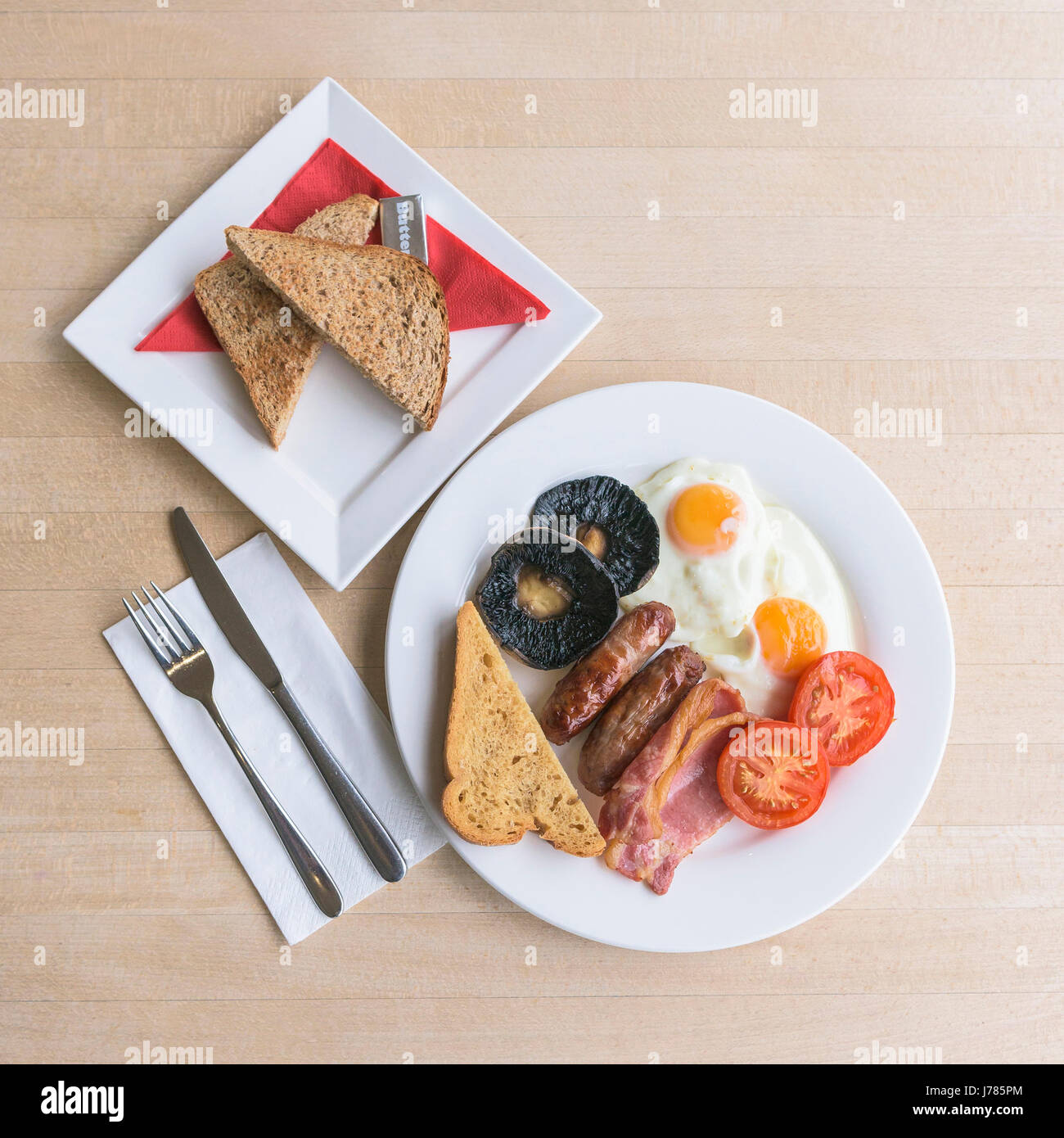 Eine Draufsicht auf ein komplettes englisches Frühstück; Essen; Mahlzeit am Morgen; Braten bis; Kalorien; Toast; Eier; Speck; Würstchen; Gebratenes Brot; Champignons; Stockfoto
