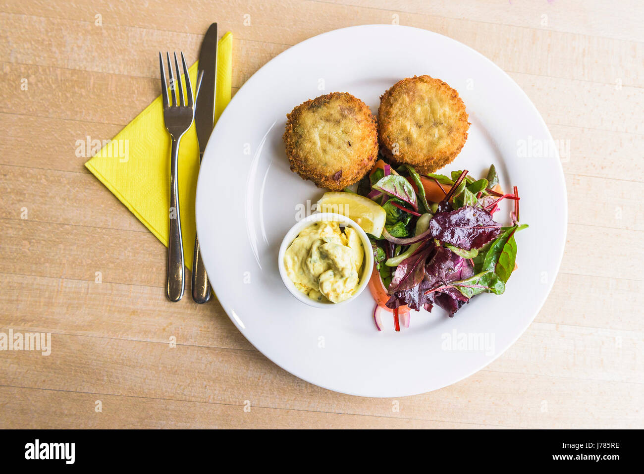 Eine Draufsicht auf eine Mahlzeit in einem Restaurant serviert; Fischfrikadellen; Salatblätter; Essen; Restaurant; Gericht; Appetitliche; Appetitlich; Besteck; Platte Stockfoto