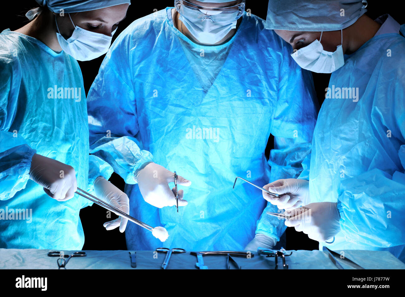 Ärzteteam Vorgang. Gruppe von Chirurgen bei der Arbeit im OP-Saal in blau getönt Stockfoto