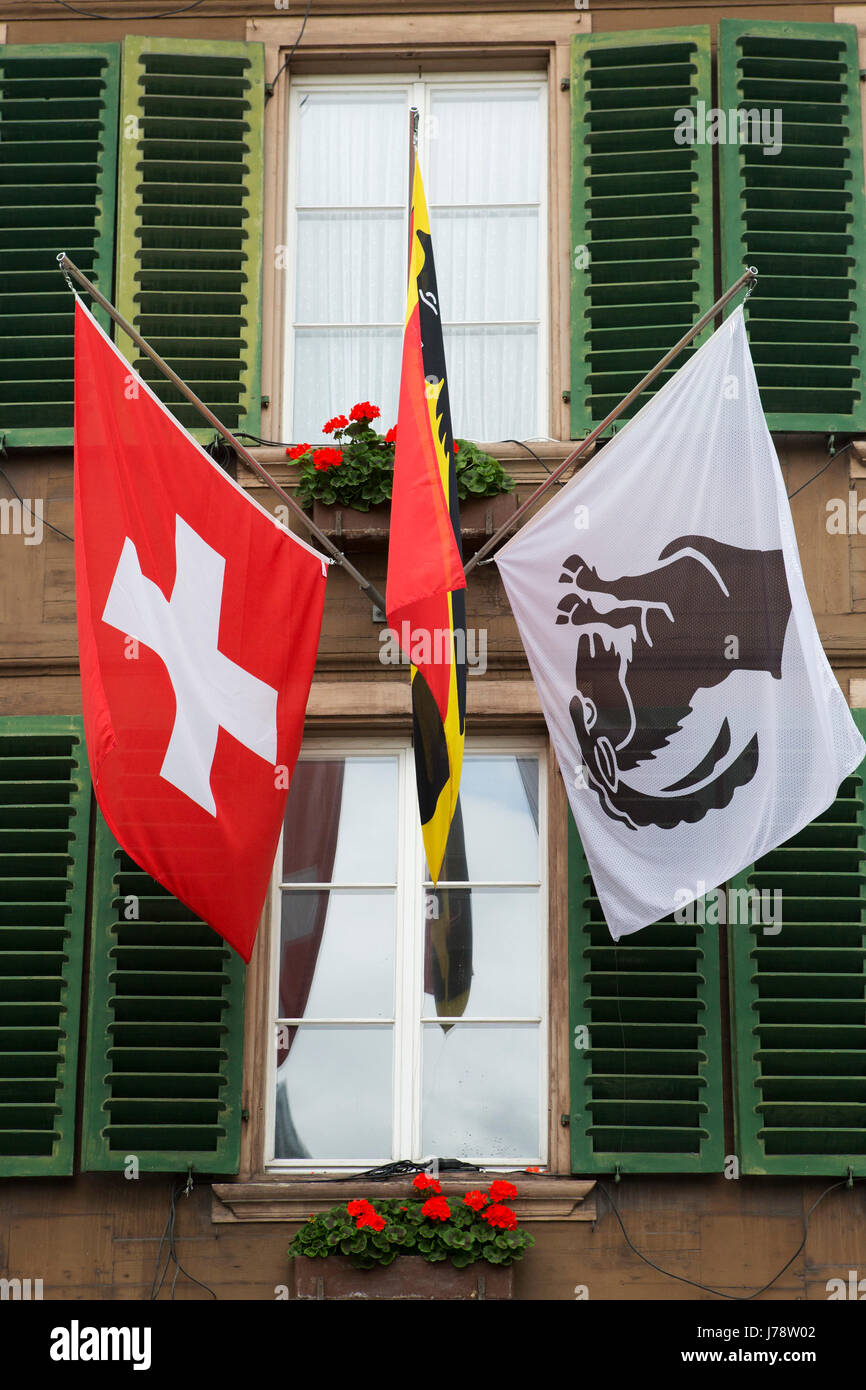 Die Flaggen der Schweiz und Interlaken an einem Gebäude in Interlaken, Schweiz. Die Gemeinde ist ein Tor zu den Alpen. Stockfoto