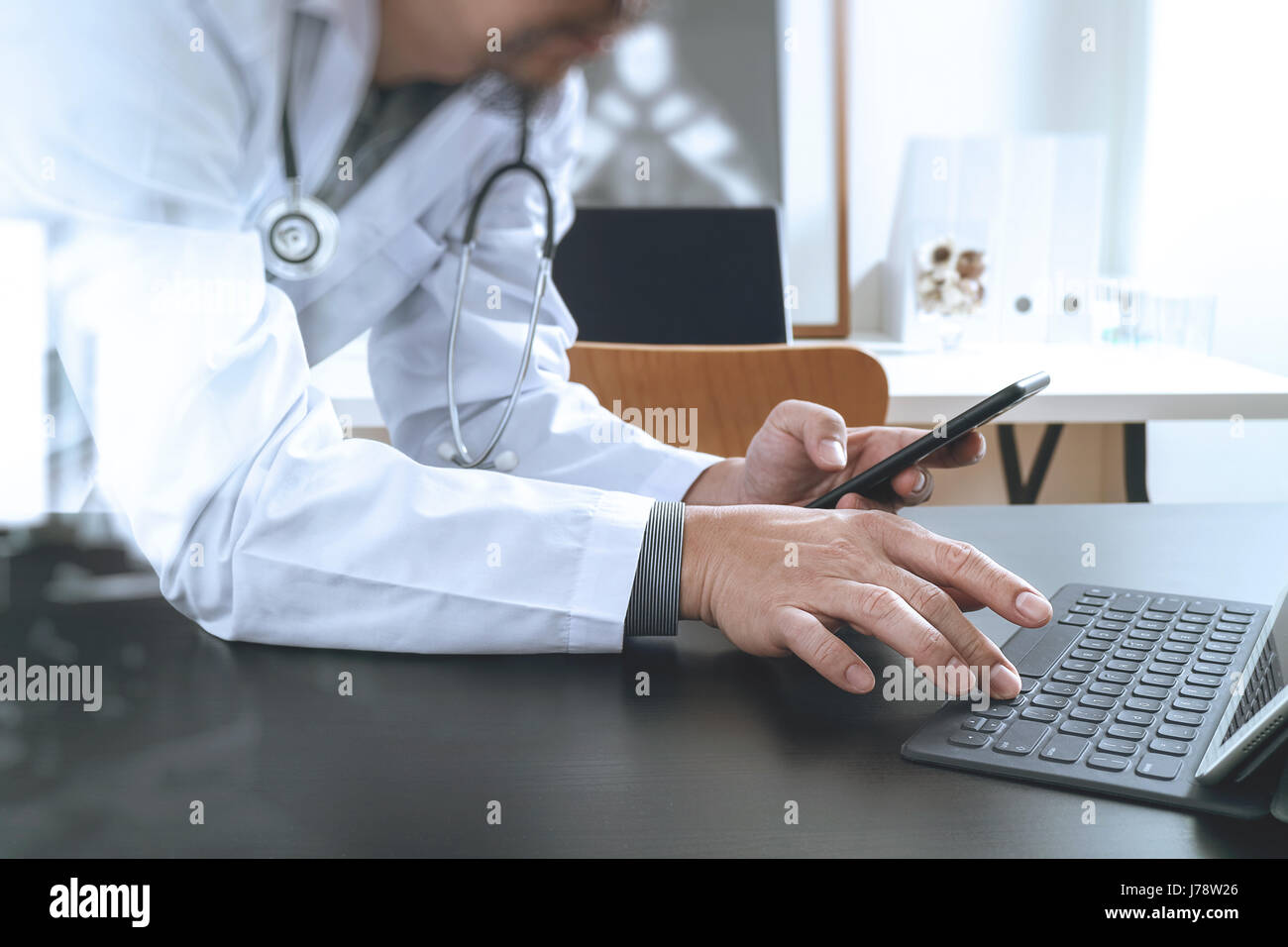 Medizintechnik-Konzept. Mit Smartphone und Stethoskop und digitale Tablet-Computer im modernen Büro im Krankenhaus tätiger Arzt Stockfoto