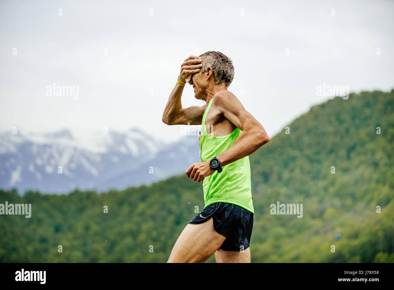 in Rennen Spring Mountain Marathon weisen alten Mann Läufer auf dem Wasser in der hand Schwamm mit Wasser Stockfoto