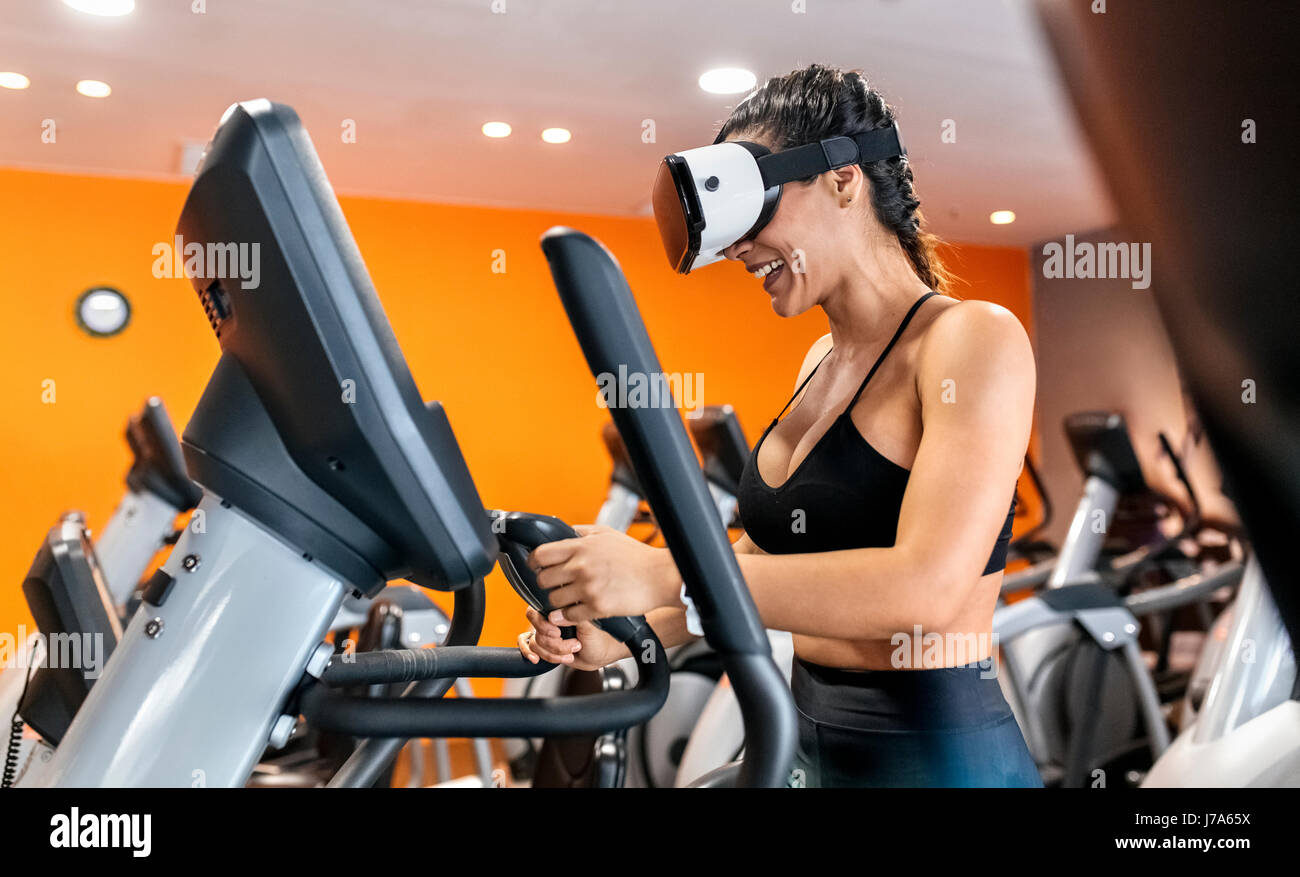 Frau mit VR-Brille auf eine elliptische Traine in der Turnhalle Stockfoto