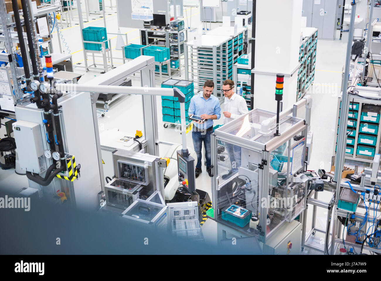 Zwei Männer mit Tablet sprechen in Fabrik Zeiterfassung/BDE Stockfoto