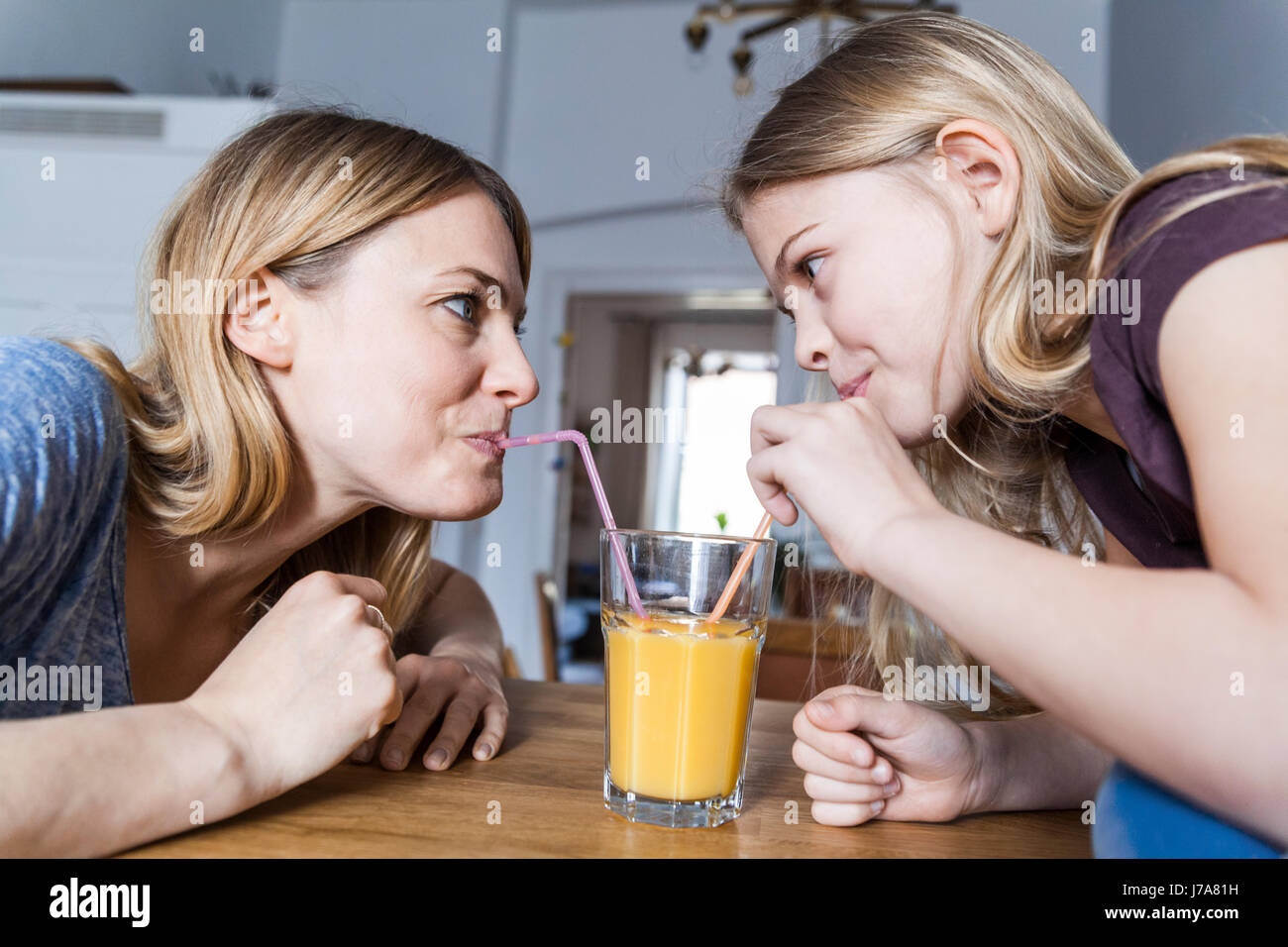 Mutter und Tochter teilen Orangensaft in Küche Stockfoto