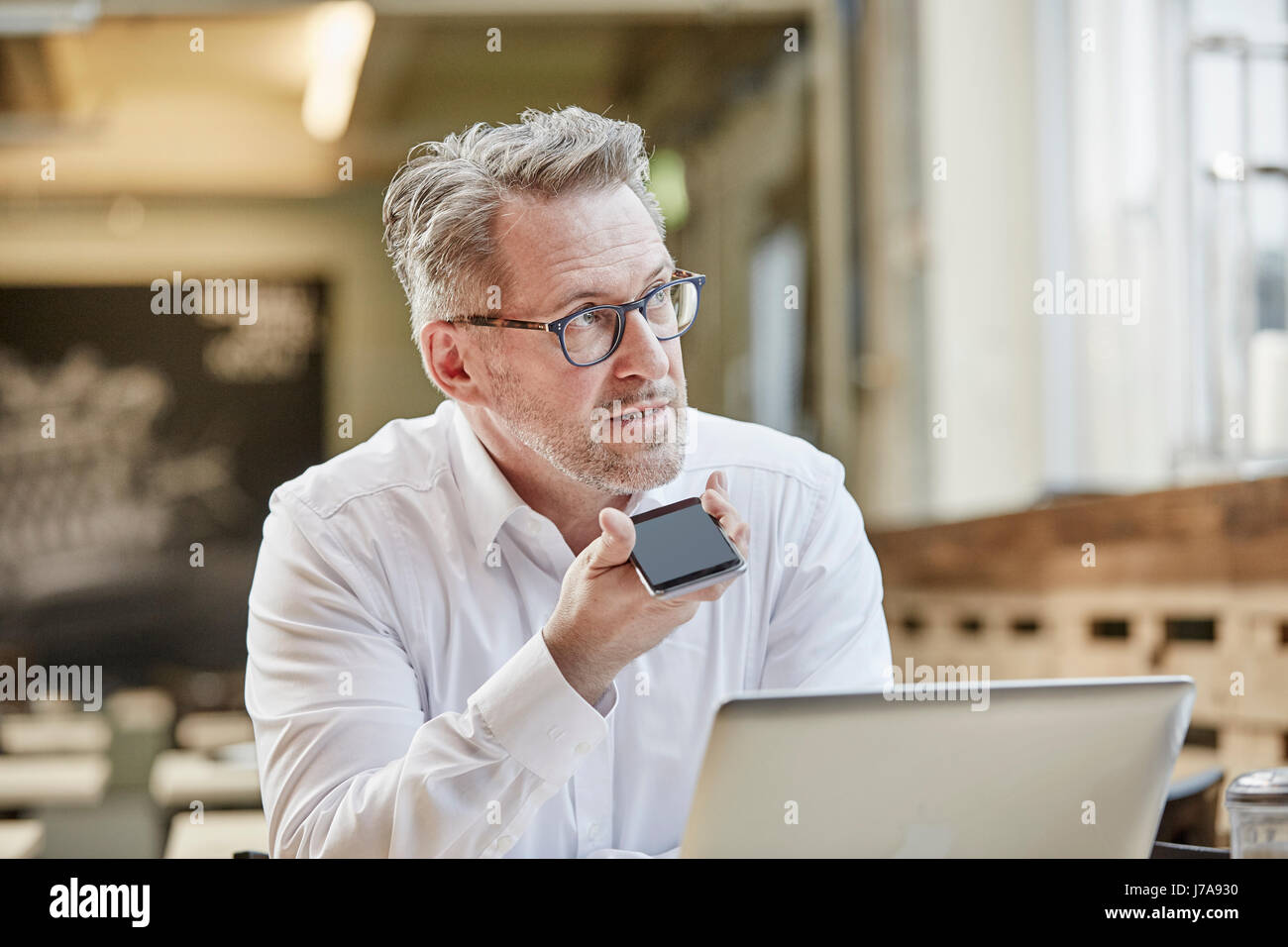 Reife Geschäftsmann im Café mit Handy Stockfoto