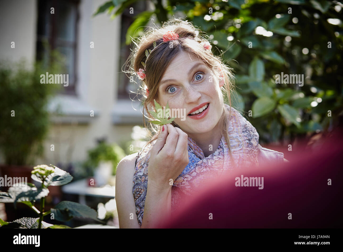 Deutschland, Hamburg, St. Pauli, Portrait einer jungen Frau hält ein Blatt treffen einen Freund Stockfoto