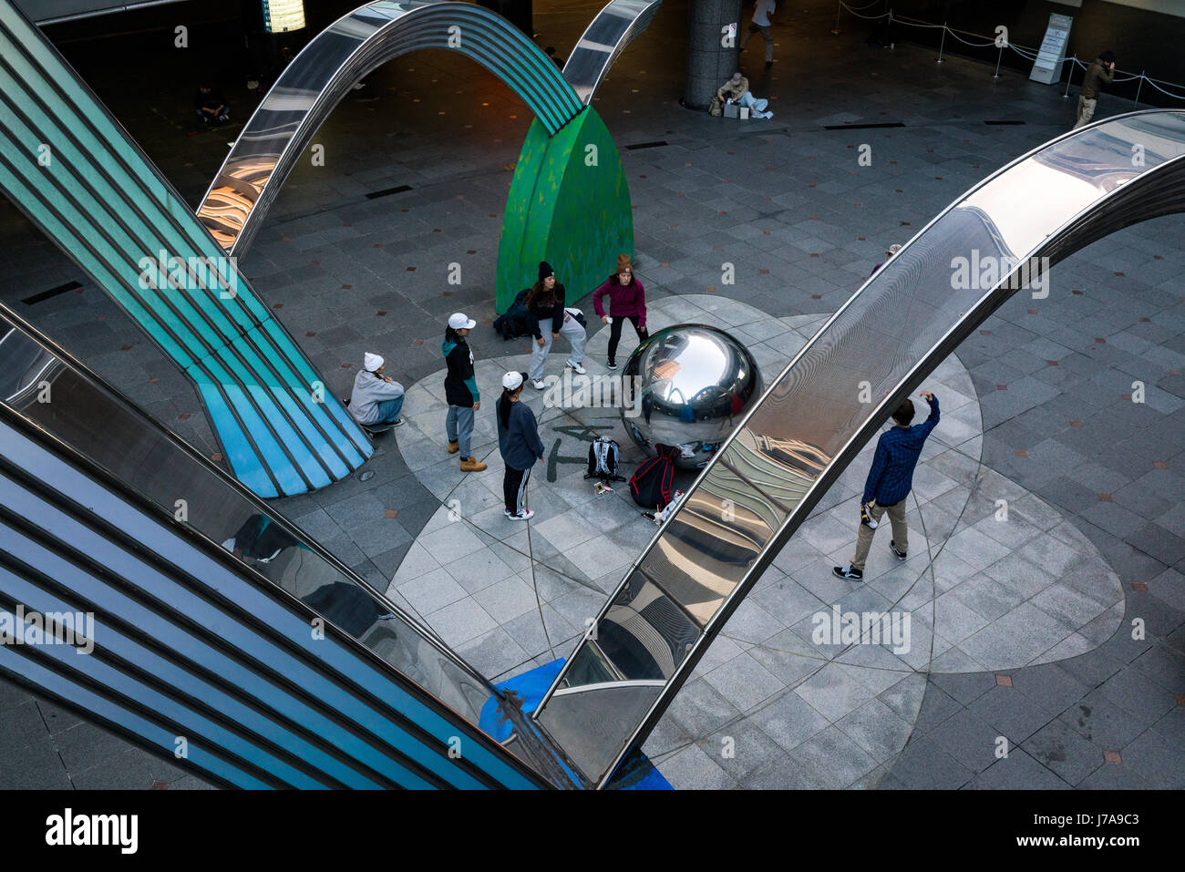 Eine Gruppe von Jugendlichen Praxis ihre hip Hop bewegt, unter Beachtung ihrer Reflexion auf der Kugel in der Mitte der Skulptur. Tagsüber Foto. Stockfoto