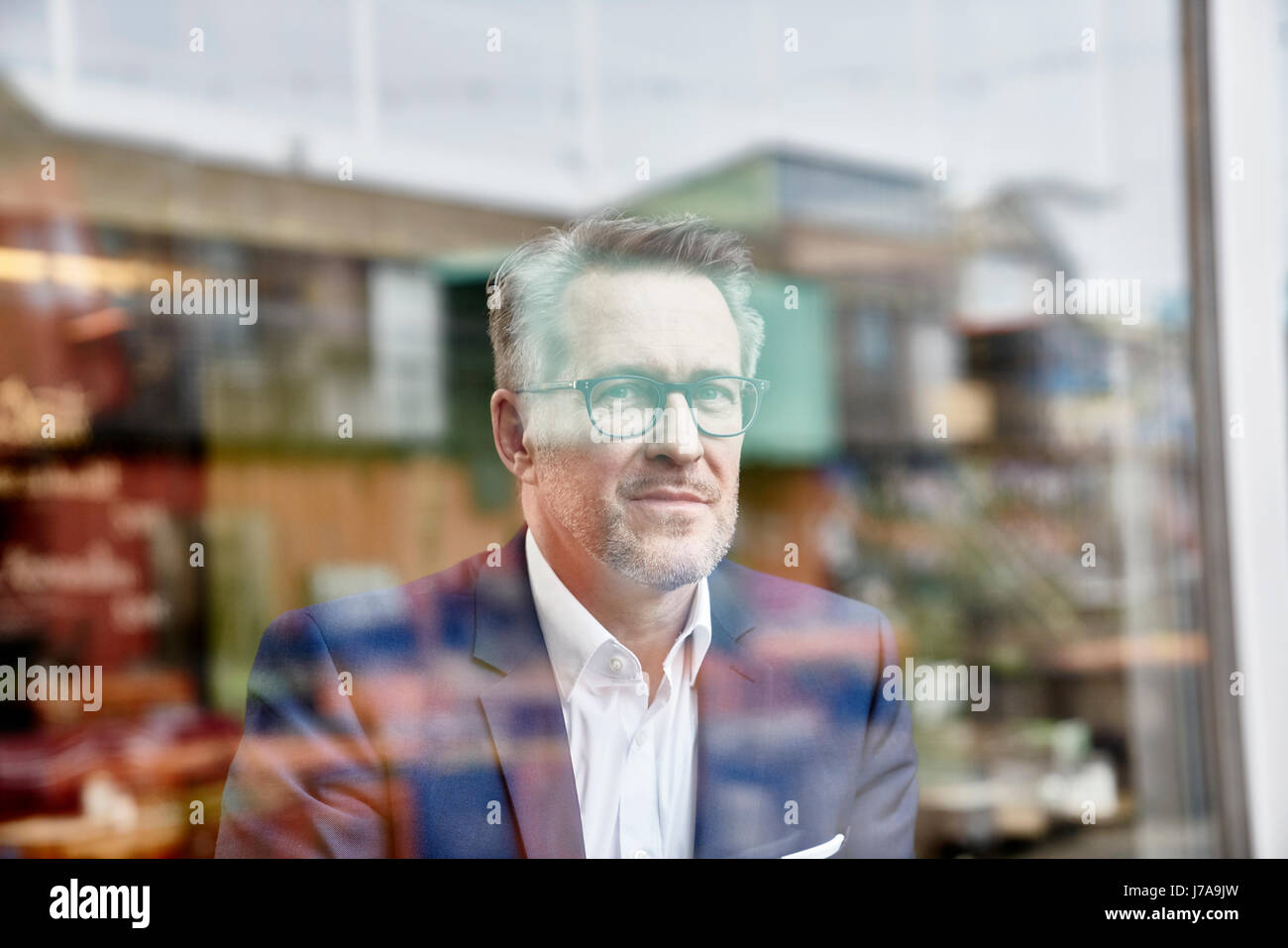 Porträt von zuversichtlich reifer Geschäftsmann hinter Fensterscheibe Stockfoto