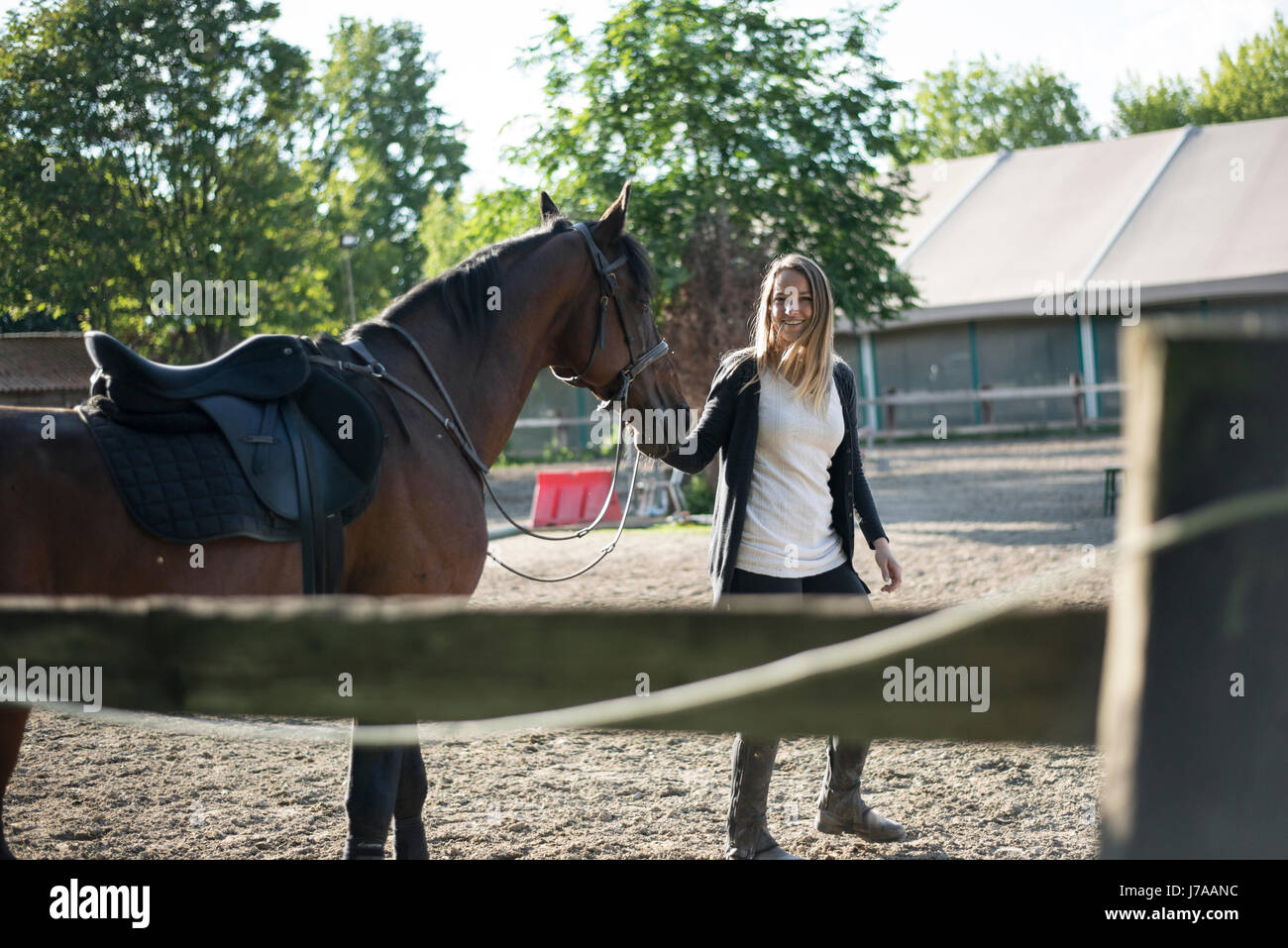 Lächelnde junge Frau mit Pferd am Bauernhof Stockfoto