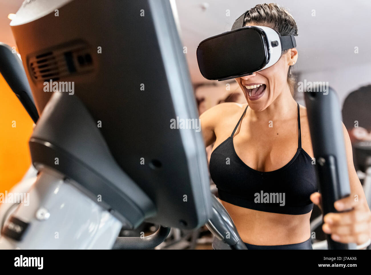 Frau mit VR-Brille auf eine elliptische Traine in der Turnhalle Stockfoto