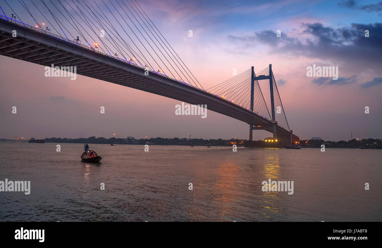 Vidyasagar setu Brücke bei Dämmerung mit einem hölzernen Boot auf dem Fluss Hooghly. Stockfoto