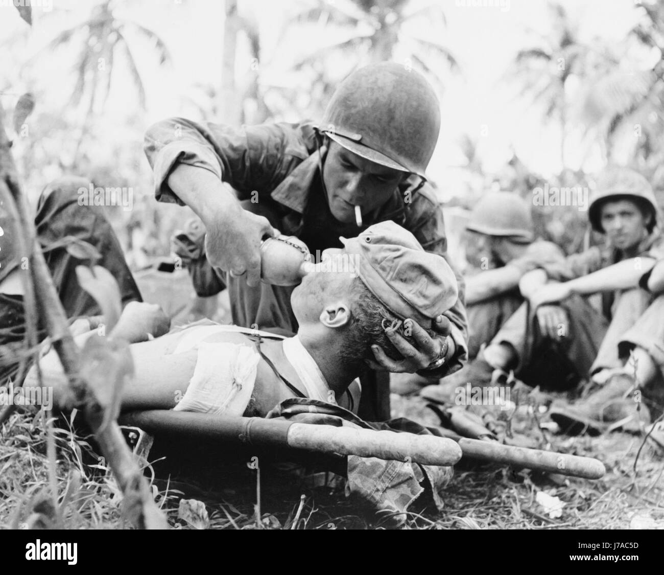 Navy Corpsman gibt Getränk zu einem verwundeten Marine in Guam, 1944. Stockfoto