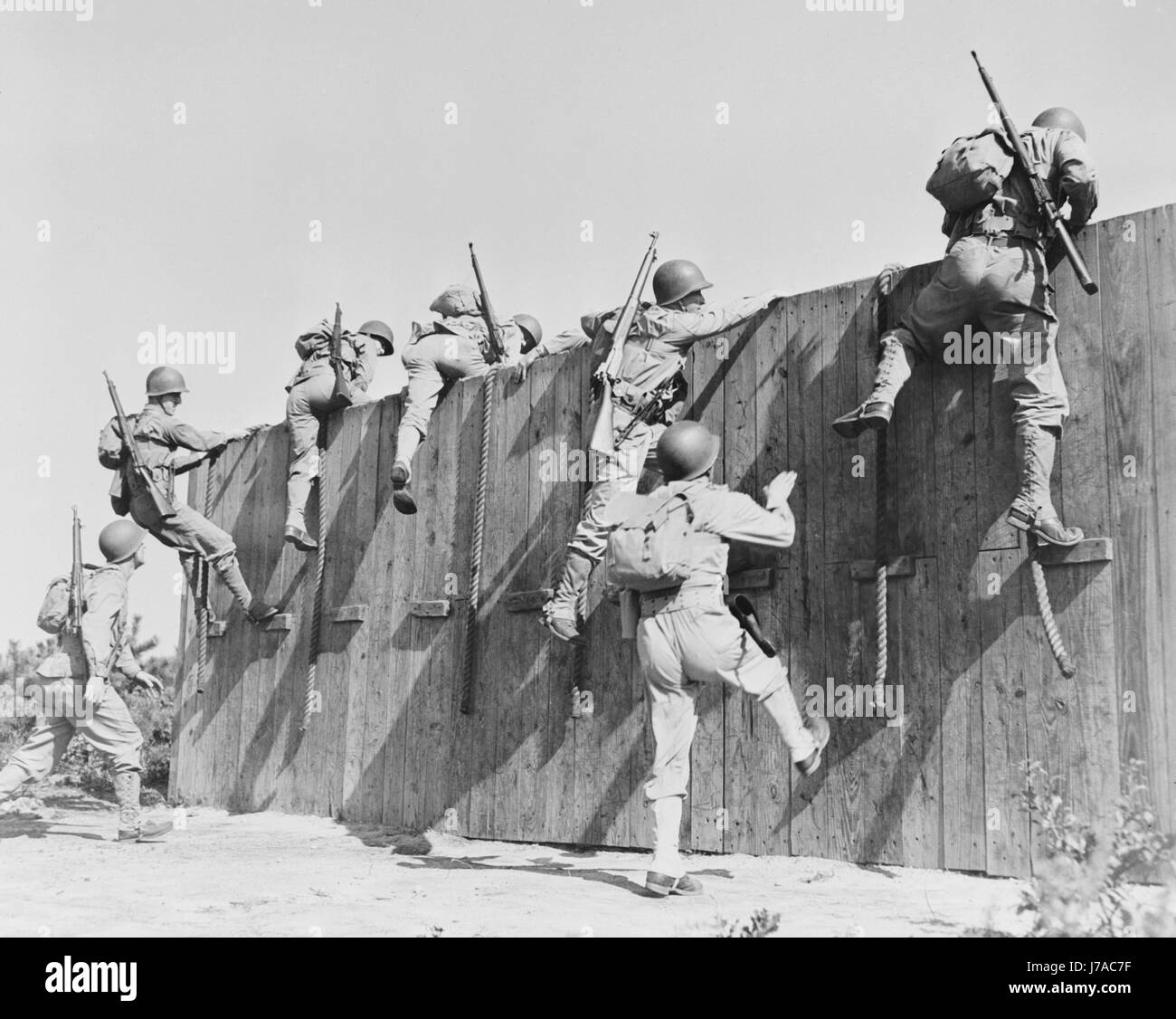 Soldaten klettern hinauf und über eine Wand im Camp Edwards, Massachusetts, ca. 1942. Stockfoto