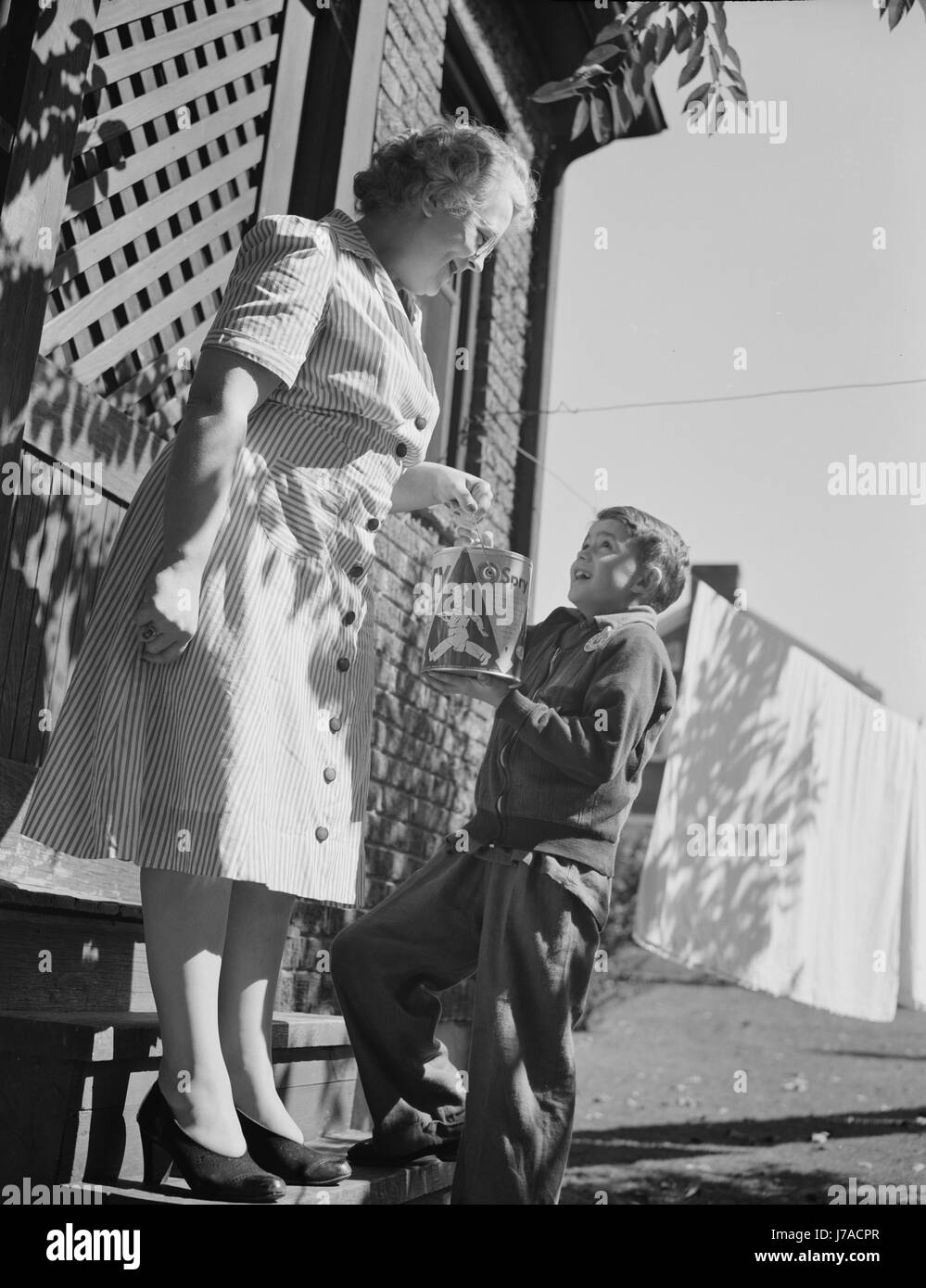 Ein kleiner Junge sammelt Fette und Fette aus seiner Nachbarschaft, 1942 in Kriegsmaterial, zu verarbeiten. Stockfoto