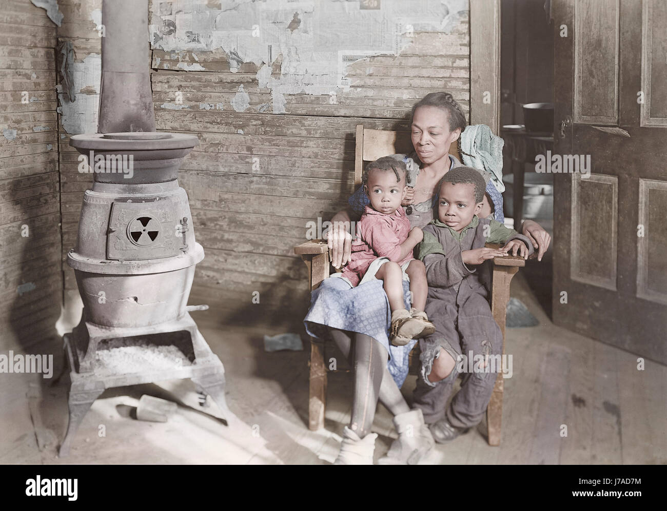 Mutter und ihre zwei Kinder sitzen mit Holzofen, 1937. Stockfoto
