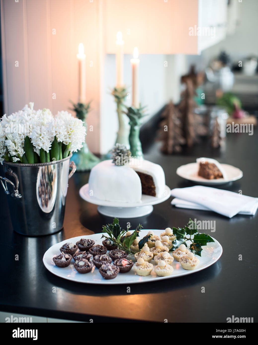 Kleine Törtchen und Weihnachtskuchen auf einem schwarzen Stein Arbeitsplatte in eleganten Candle-light-Küche Stockfoto