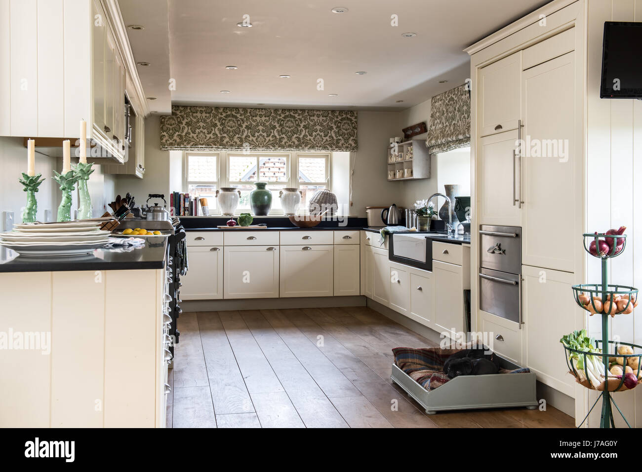 Elegante Küche mit schwarzen Stein Arbeitsplatten und bedruckte Vorhänge Stockfoto
