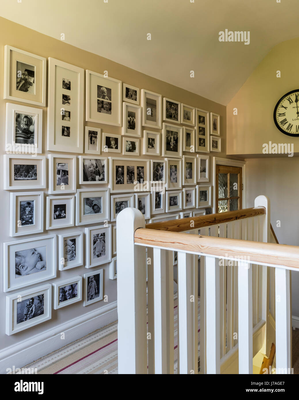 Umrahmt von schwarzen und weißen Familie Fotografie entlang Wand auf Treppe Landung Stockfoto