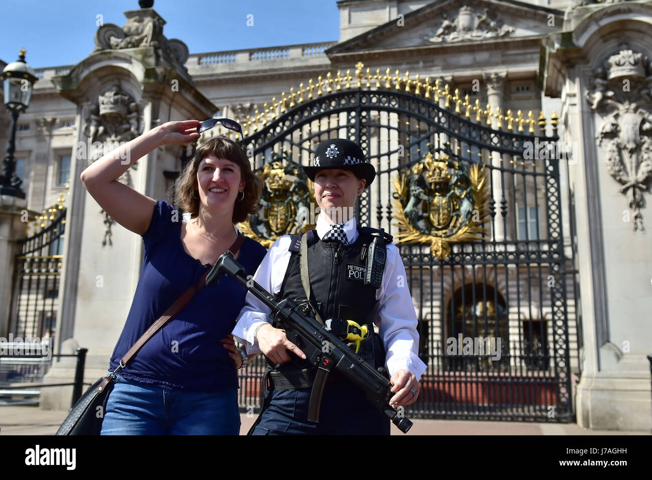 Ein Tourist posiert für ein Foto mit einem bewaffneten Polizisten außerhalb der Buckingham Palace, London, als die Wachablösung im Palazzo abgebrochen um Polizisten im Zuge des Angriffs Manchester erneut bereitstellen. Stockfoto