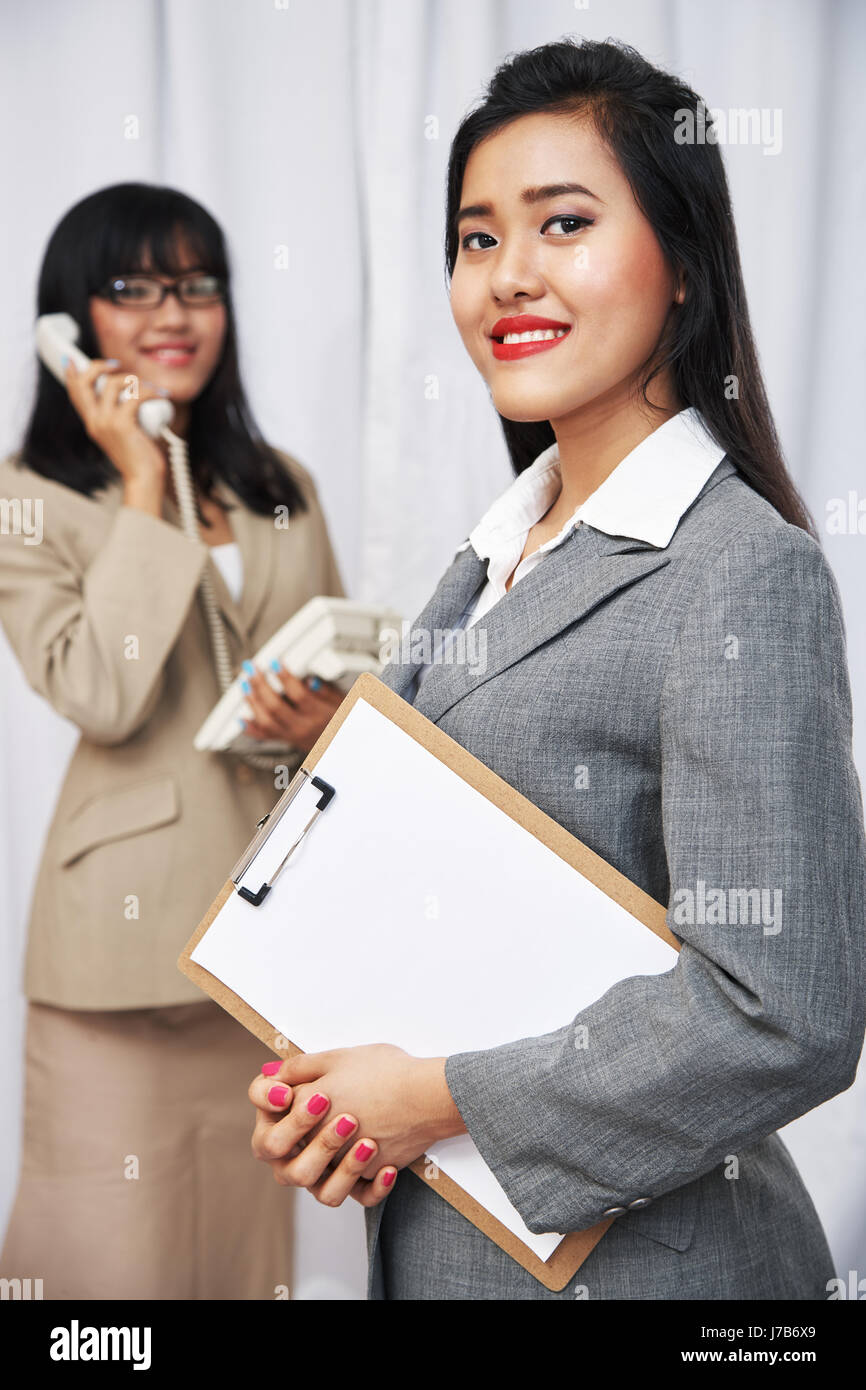 Porträt von Geschäftsfrauen tragen Anzüge stehen und Gelenkarme Stockfoto