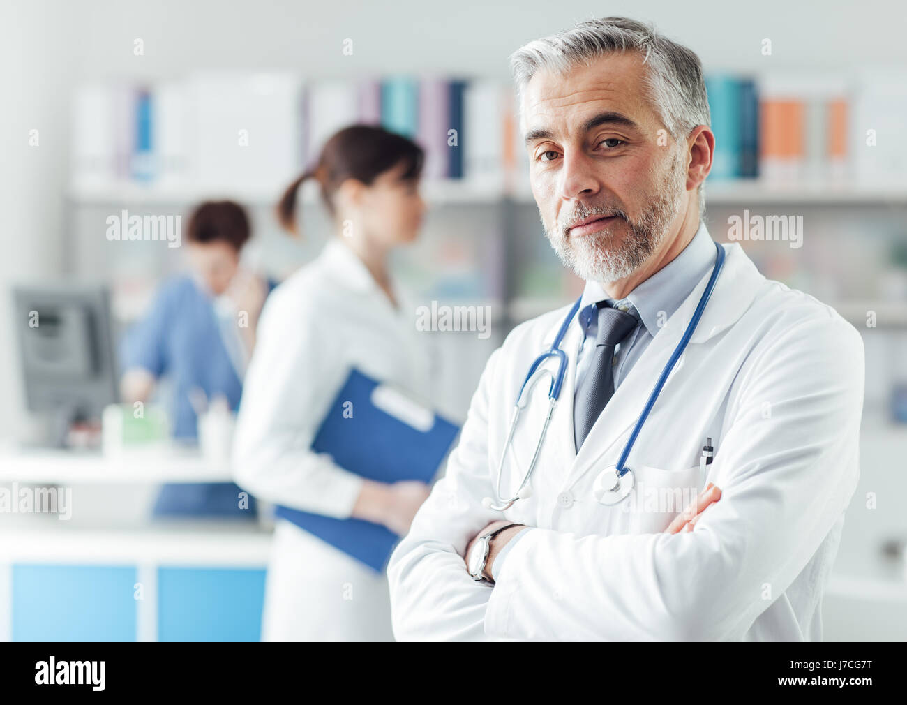 Zuversichtlich professionellen Arzt posiert im Büro mit verschränkten Armen und Blick in die Kamera Stockfoto