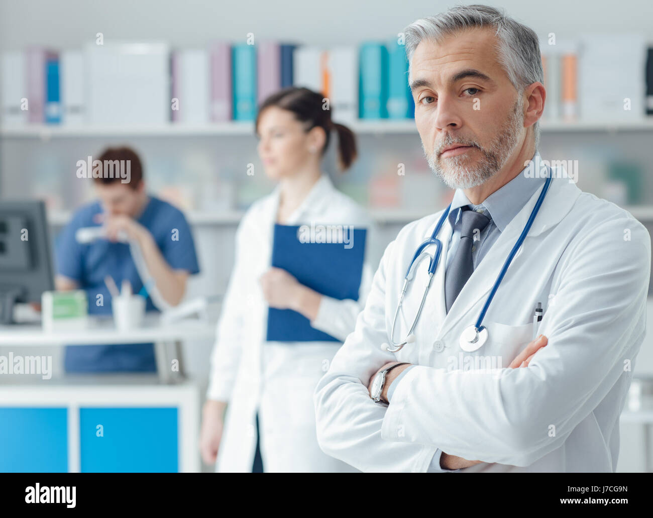 Zuversichtlich professionellen Arzt posiert im Büro mit verschränkten Armen und Blick in die Kamera Stockfoto