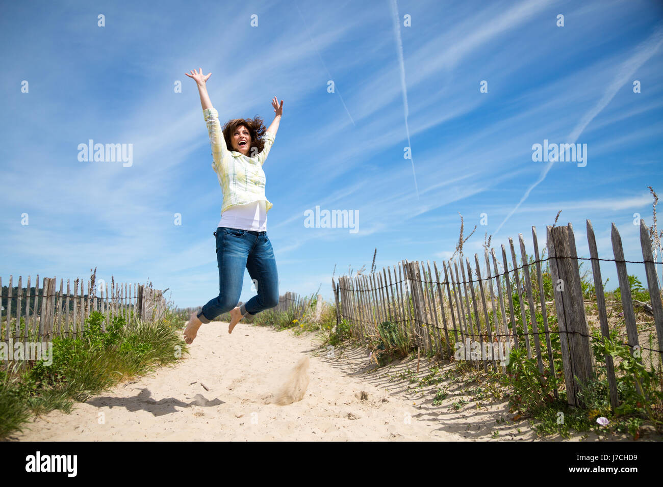 Glücklich mittleren gealterten Frau springen auf den Strand-verrückten für Urlaub Stockfoto