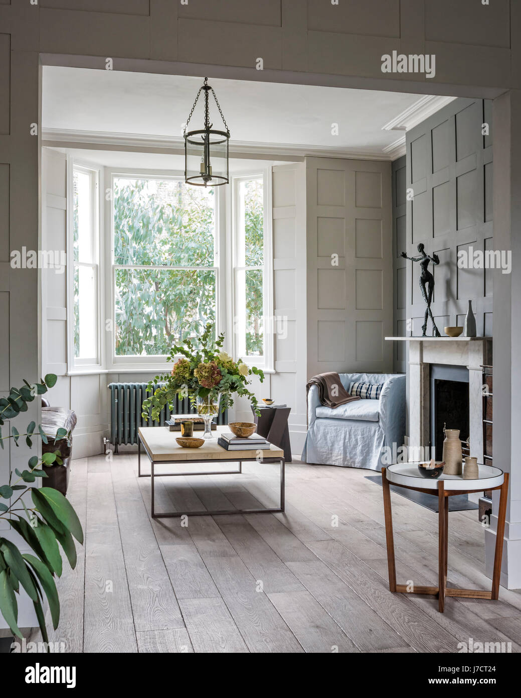 Holz und Metall Couchtisch aus albrissi in Wohnzimmer mit Wandverkleidungen und schrubben Holzböden. Die kleine Sessel ist in Leinen fr gepolstert Stockfoto