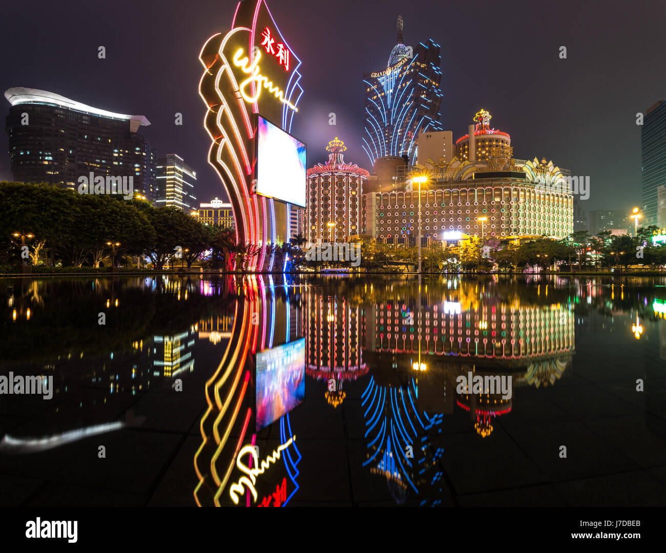 Macao, CHINA - 23. April 2017: Die Lichter von einem berühmten Casino-Betreiber Wynn reflektieren auf dem Wasser mit dem Lisboa Casino-Turm im Hintergrund. Macau rece Stockfoto