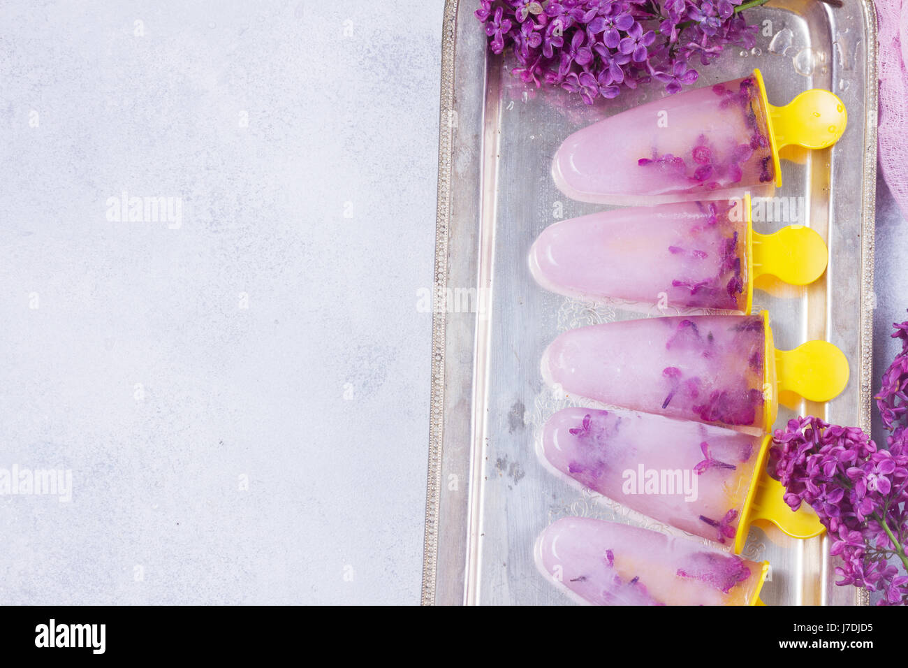 Eis am Stiel mit lila Blumen Stockfoto