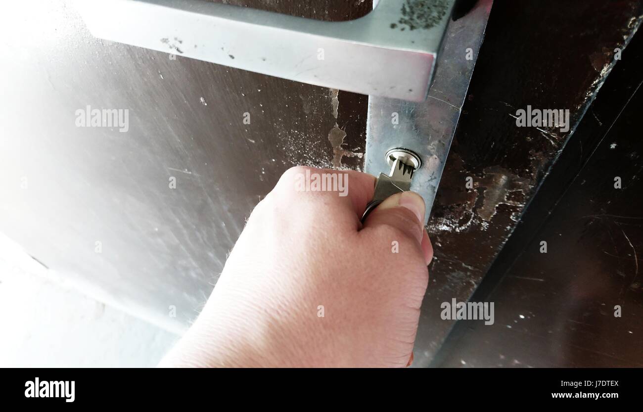 Nahaufnahme der Hand mit Schlüssel entriegeln der metallischen Tür. Stockfoto