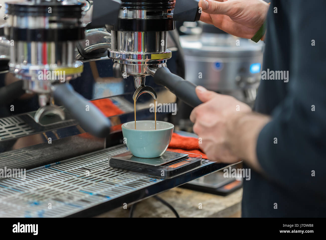 Close-up Ansicht Hände von professionellen Barista im Kaffeehaus Zubereitung Espresso, Kaffeemaschine, gießt frisches Getränk in Porzellantasse beenden warten Stockfoto