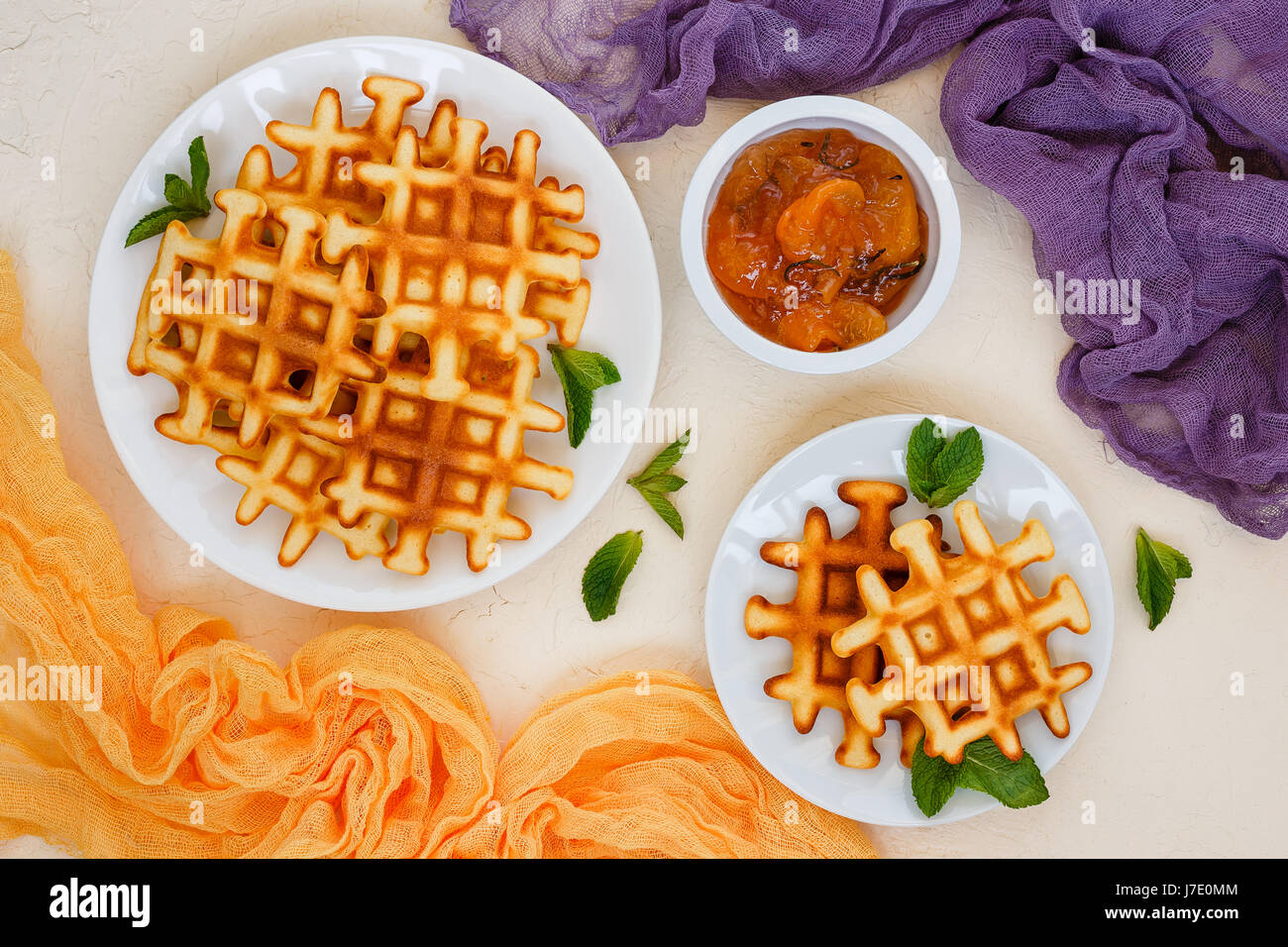 Zwei Platten der belgische Waffeln garniert mit Minze und Pfirsichmarmelade mit Rosmarin in kleinen Schüssel. Ansicht von oben. Stockfoto