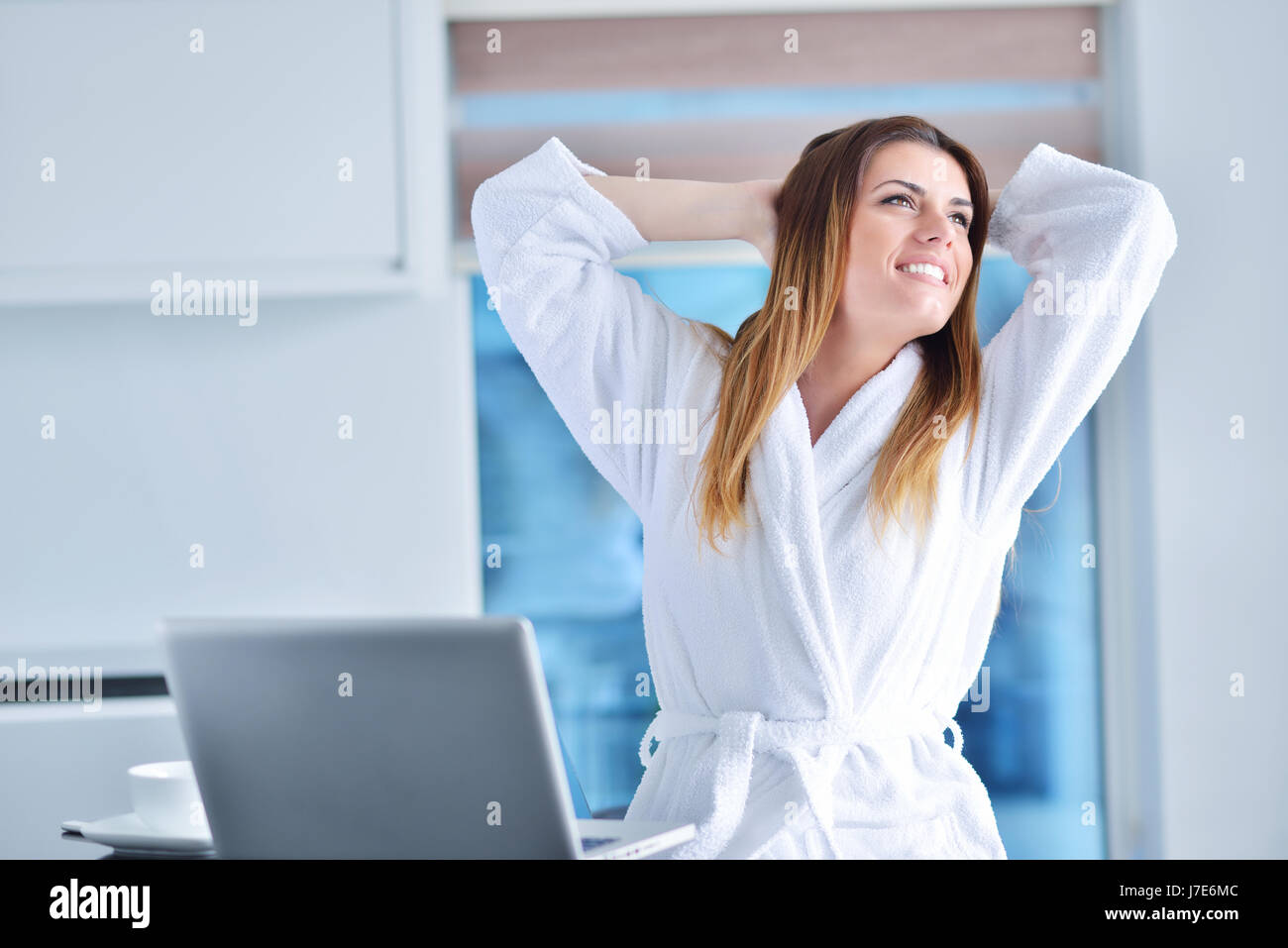 Frau trägt einen weißen Bademantel mit laptop Stockfoto