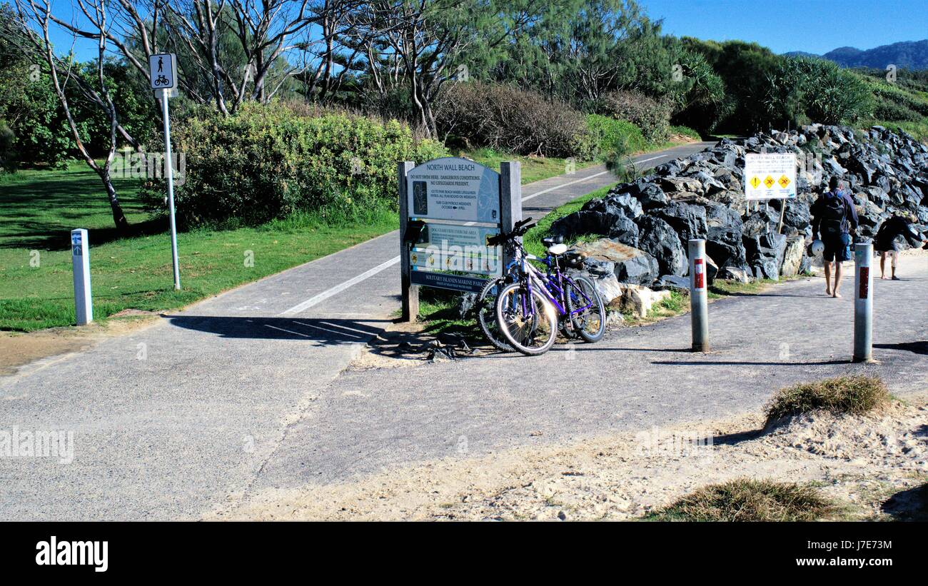 Melden Sie an Board sagen Wand Nordstrand, zwei Fahrräder, zwei Personen in Coffs Harbour, New South Wales, Australien. Stockfoto