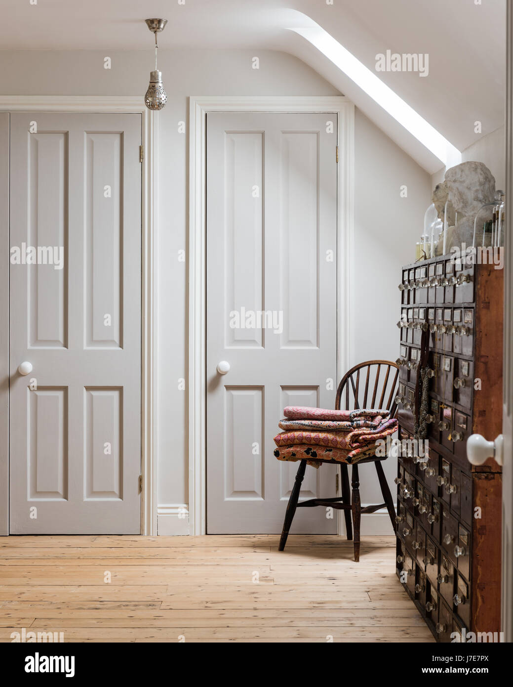 Antike Apothekerschrank in Zimmer mit Holzdielen und Windsor Stuhl. Die Schranktüren sind Elefanten Atem von Farrow & Ball gemalt. Stockfoto