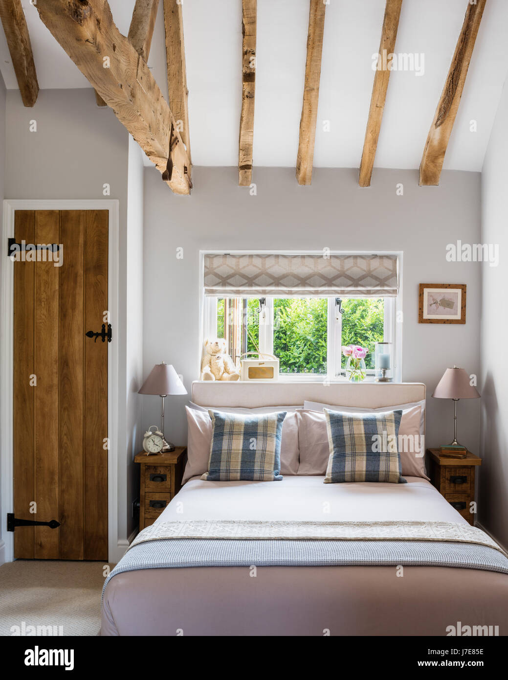 Gemütliches Schlafzimmer mit Holzbalken und schmale Brett Nachttische aus Indigo Möbel. Stockfoto