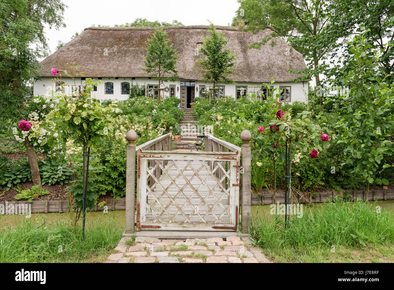 Gated Steg Zugang zum Garten der strohgedeckten 17. Jahrhundert Famhouse, erbaut im 12. Jahrhundert Earthmound um Überschwemmungen zu verhindern Stockfoto