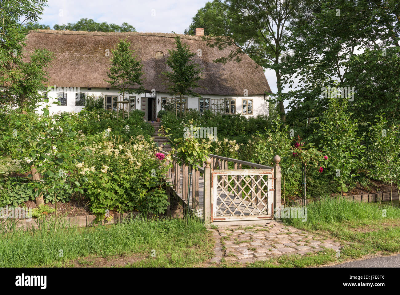 Gated Fußgängerbrücke und Garten der strohgedeckten 17. Jahrhundert Famhouse, erbaut im 12. Jahrhundert Earthmound um Überschwemmungen zu verhindern Stockfoto