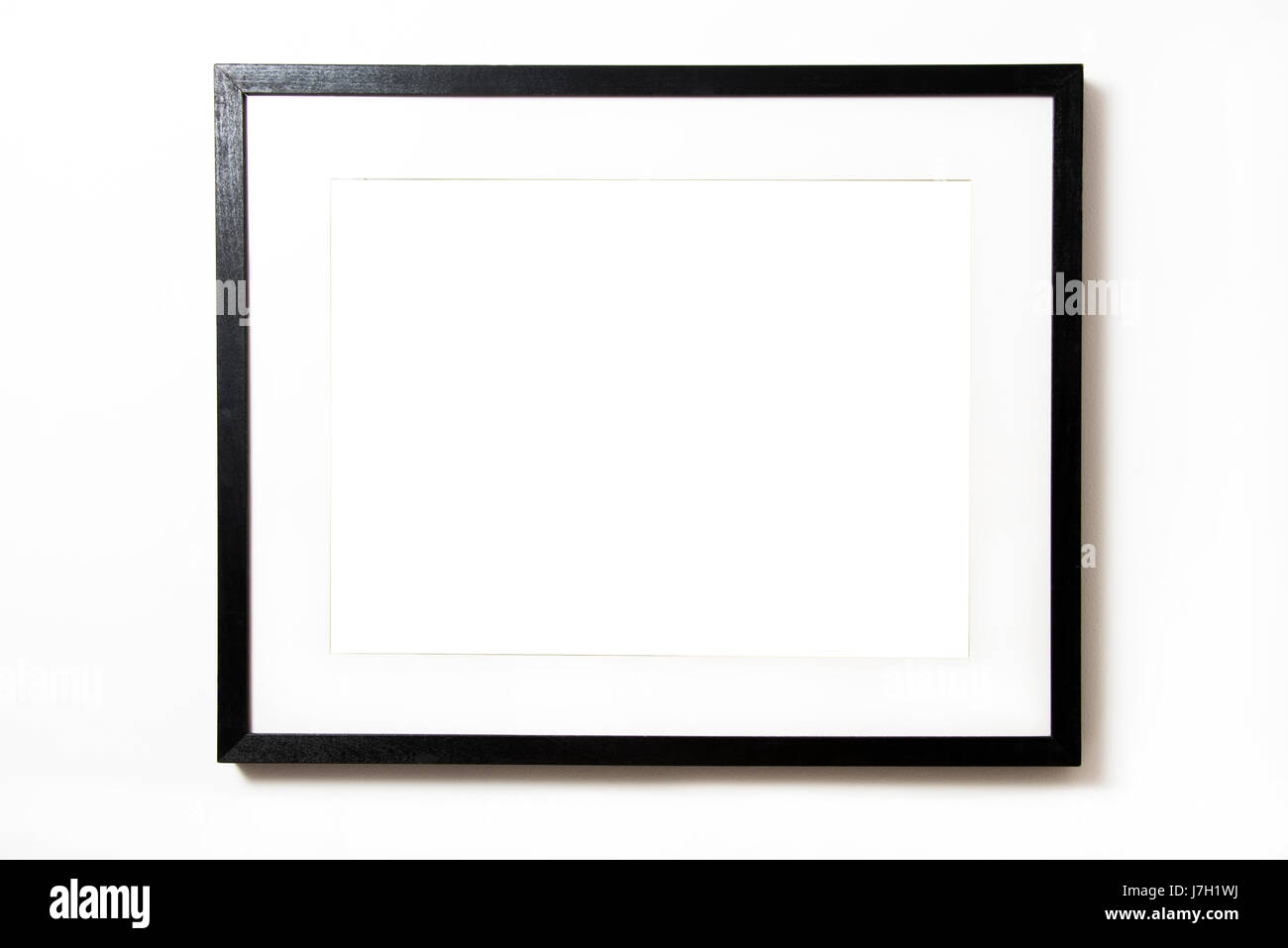 Schwarzen rechteckigen Rahmen mit Matte, leere im Inneren auf einer weißen Wand hängen Stockfoto