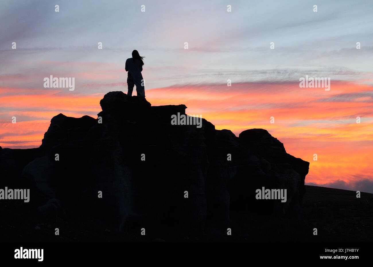 Lanzarote-Sonnenuntergang - eine Frau steht auf einem vulkanischen Felsen bei Sonnenuntergang, Lanzarote, Kanarische Inseln, Europa Stockfoto