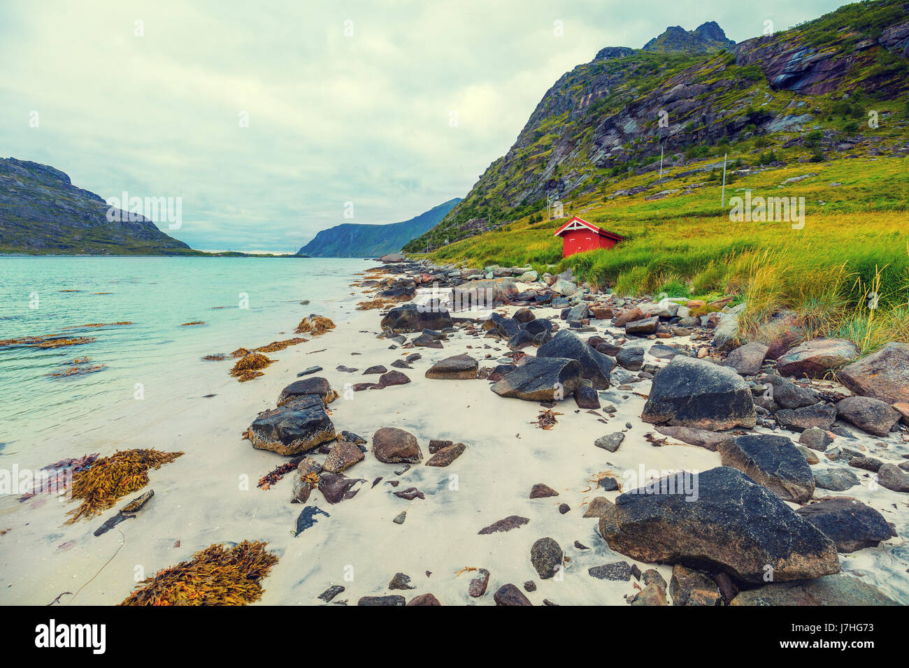 Fjord bei Regenwetter. Felsiger Strand am Abend, weißen Sand am Strand. Schöne Natur Norwegens. Lofoten-Inseln. Angeln-Haus am Strand Stockfoto