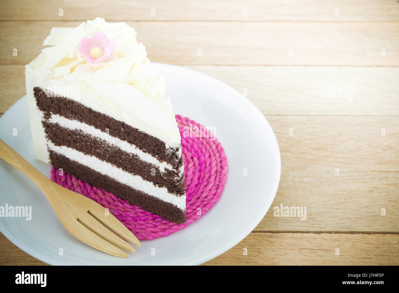 Stück Schokoladenkuchen mit Blume auf Holz Hintergrund Stockfoto