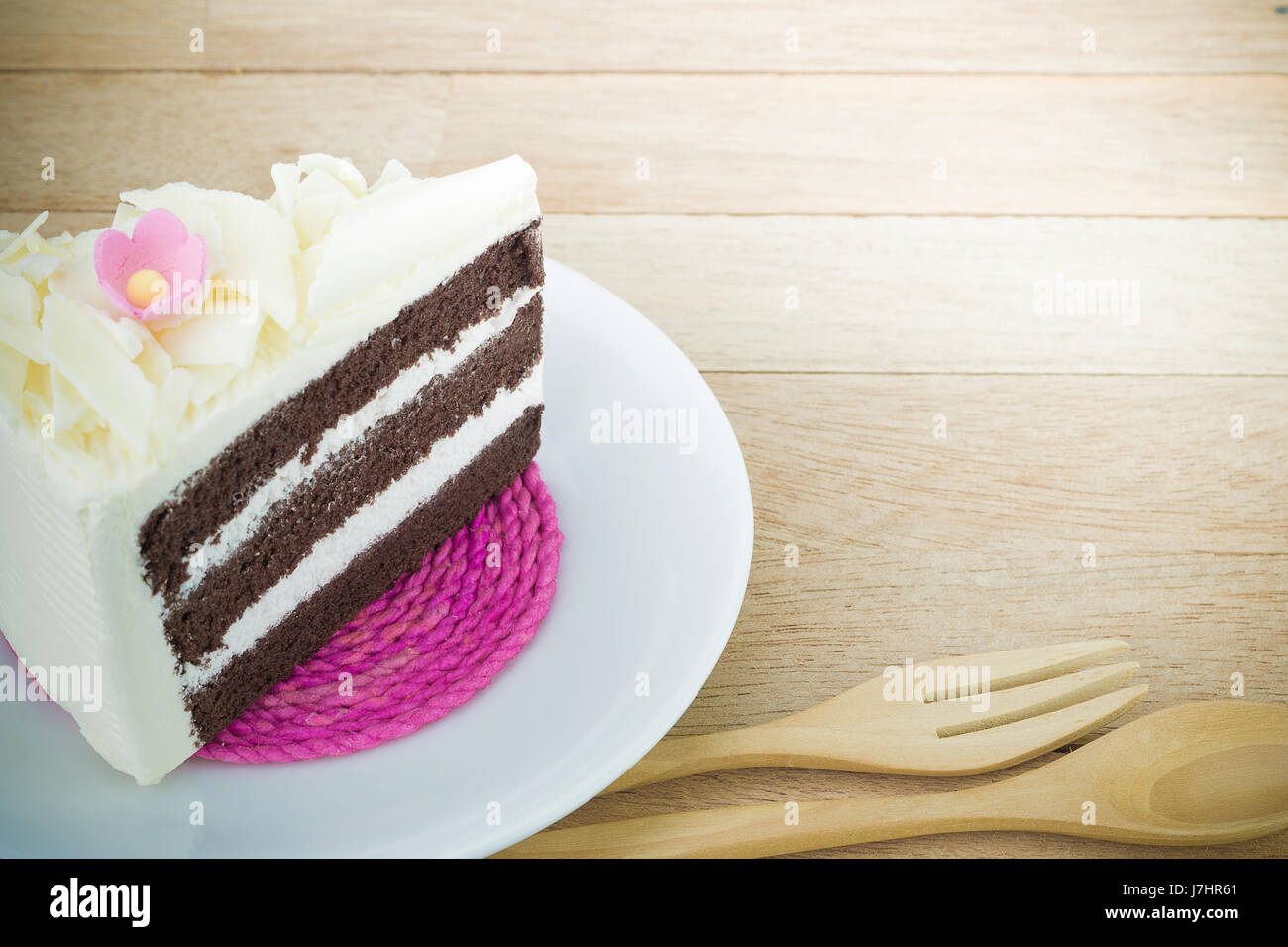 Stück Schokoladenkuchen mit Blume auf Holz Hintergrund Stockfoto