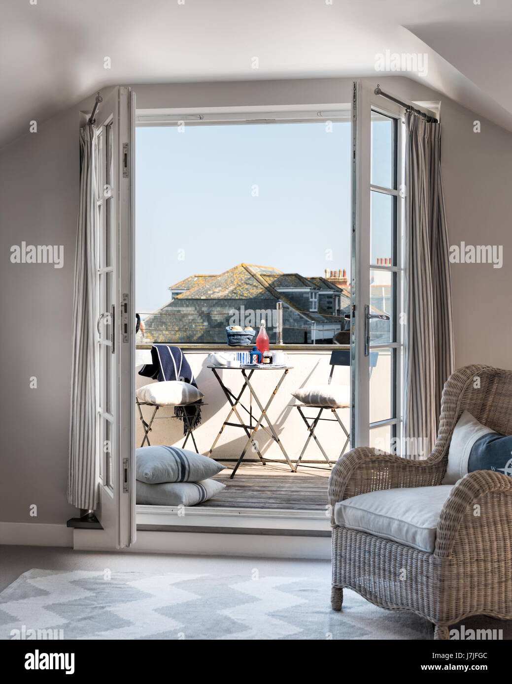 Blick durch offene Türen, Balkon mit Blick auf den Hafen geschmückt. Rattan Sessel ist aus The Country Home Stockfoto